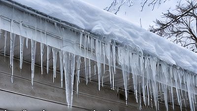 Ice dam and icicles forming along the eave of a Minnesota home in winter